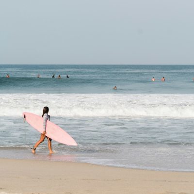 Young girl holding surfboard on Zicatela beach in Puerto Escondido